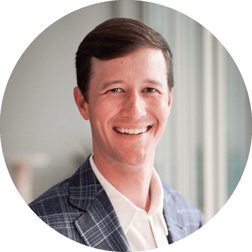 A man in a checked blazer and white shirt is smiling in a professional headshot.